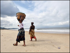 Women vendors walk on the beach in Freetown