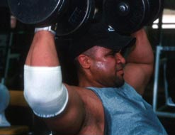 man sweating, lifting weights in a gym
