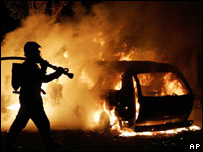 Bombeiro tenta apagar incêndio em um carro em "Les Musicians", um complexo habitacional do subúrbio de Les Mureaux, noroeste de Paris, no sábado, 5 de novembro.