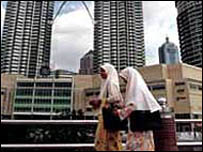 Malezya'da, Petronas kuleleri önünde yürüyen iki kadın