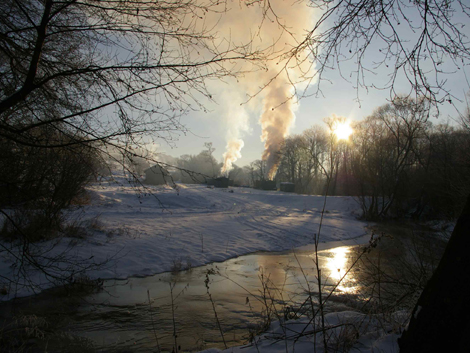 Clouds of smoke overhead a snowy landscape in winter in Poland