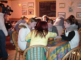 Criw yn eistedd rownd byrddau