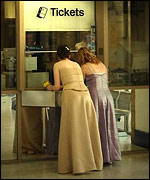 Girls in dresses buying train tickets