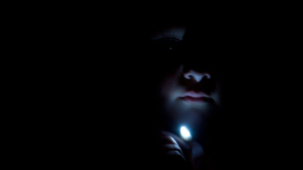 Colin Strain holds a torch under his chin to create a spooky image