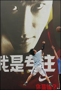 Boys playing basketball in front of advert of Liu Xiang