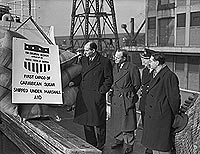 Marshall Aid sugar is unloaded at London's Royal Victoria Dock, February 1947, watched by US and UK officials