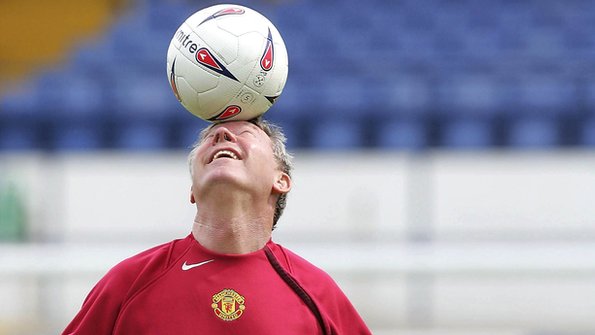 Sir Alex Ferguson balances a football on his head