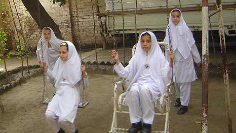 Girls wearing white and playing on the swings