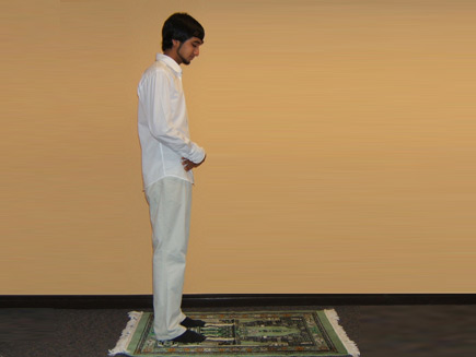 A man stands with his right hand over his left hand on his navel