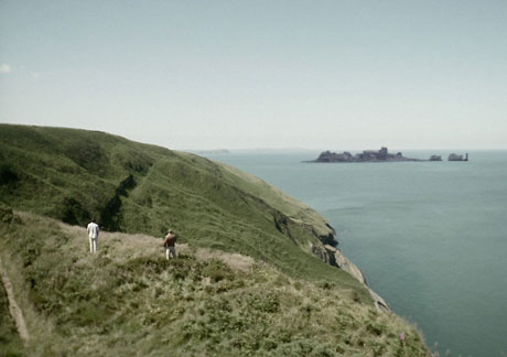 The actors view the spectacular Pembrokeshire scenery, with added rock formation, the Devil's Bridge of the film's title. Photo © Dogs Of Annwn Ltd.