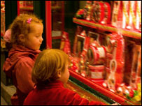 children in front of glistening Christmas presents in a shop