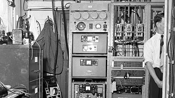 Black and white photo of office with cabinets of 1950s electronics