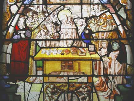 St Bernard stands in front of a desk laden with books, surrounded by people