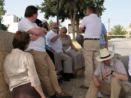 Contributors sit on the roadside. Left to right: Christine Morgan, Canon Chris Chivers, Anjum Anwar, Dr Musharraf Hussain, Rabbi Dr Alan Unterman, Becky Harris, Ernie Rea, Phil Booth (obscured) and Philip Billson