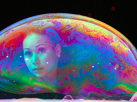 Bubble artist Melody Yang looks through a large bubble on a table. 