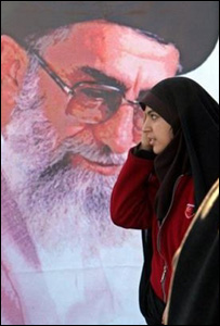 Mulher passa em frente a cartaz do aiatolá Ali Khamenei